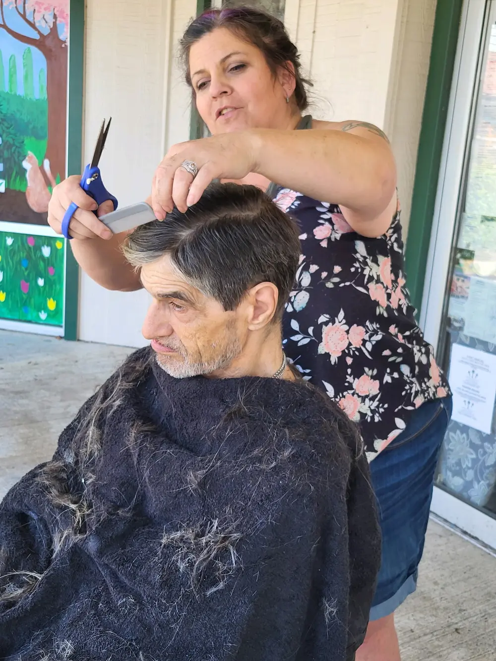 Angel Sheets giving a community member a haircut outside GG's House