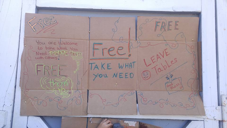 Handwritten cardboard signs reading Free and Take What You Need