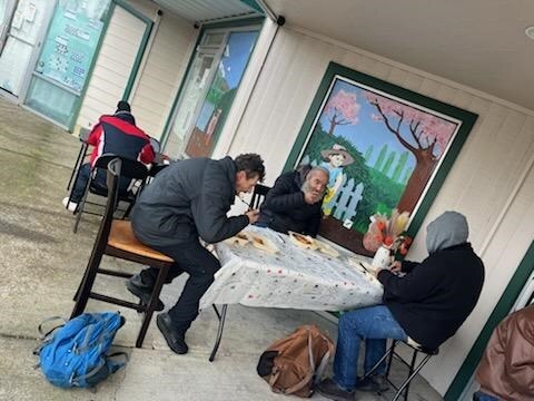 People seated together outdoors while sharing a Thanksgiving meal at GG's House
