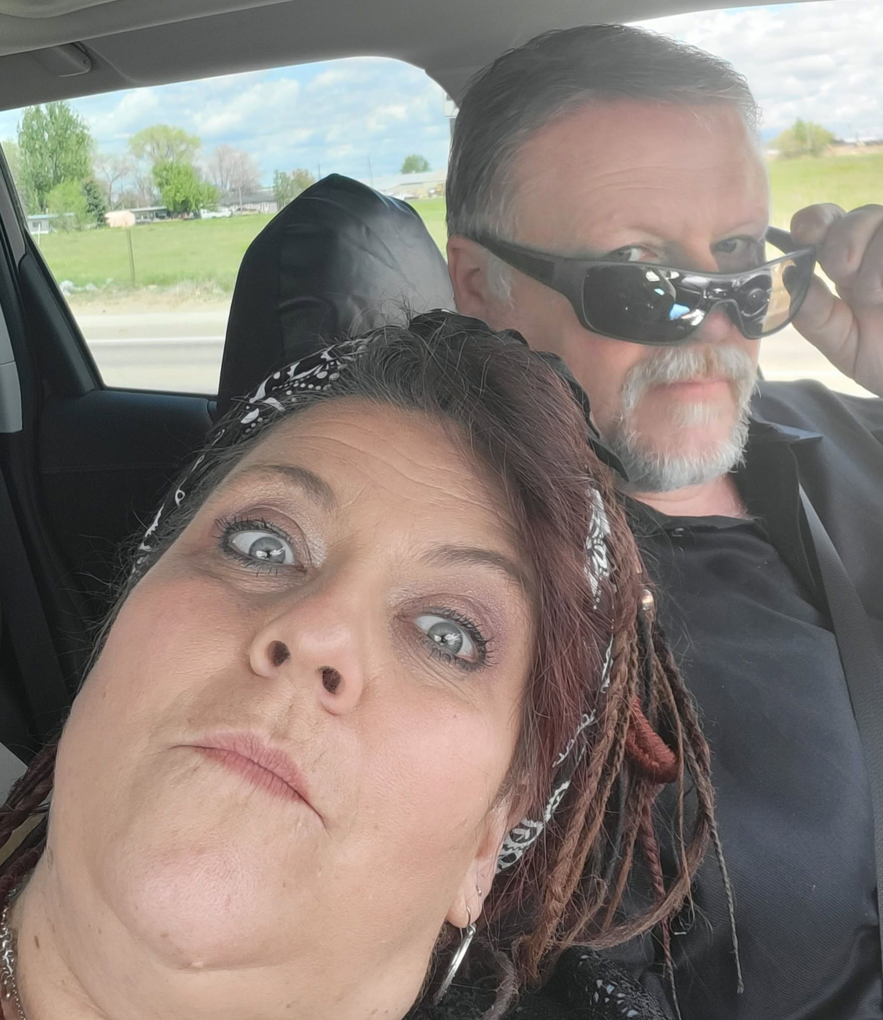 Angel making a playful face while Steve sits beside her in the car