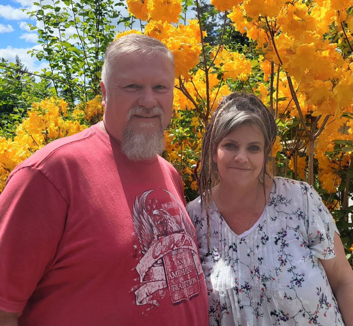 Steve and Angel smiling together among fall flowers