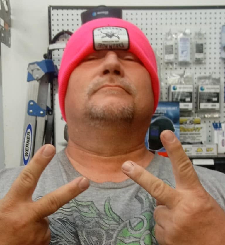 Steve Sheets wearing a bright red beanie and flashing a peace sign